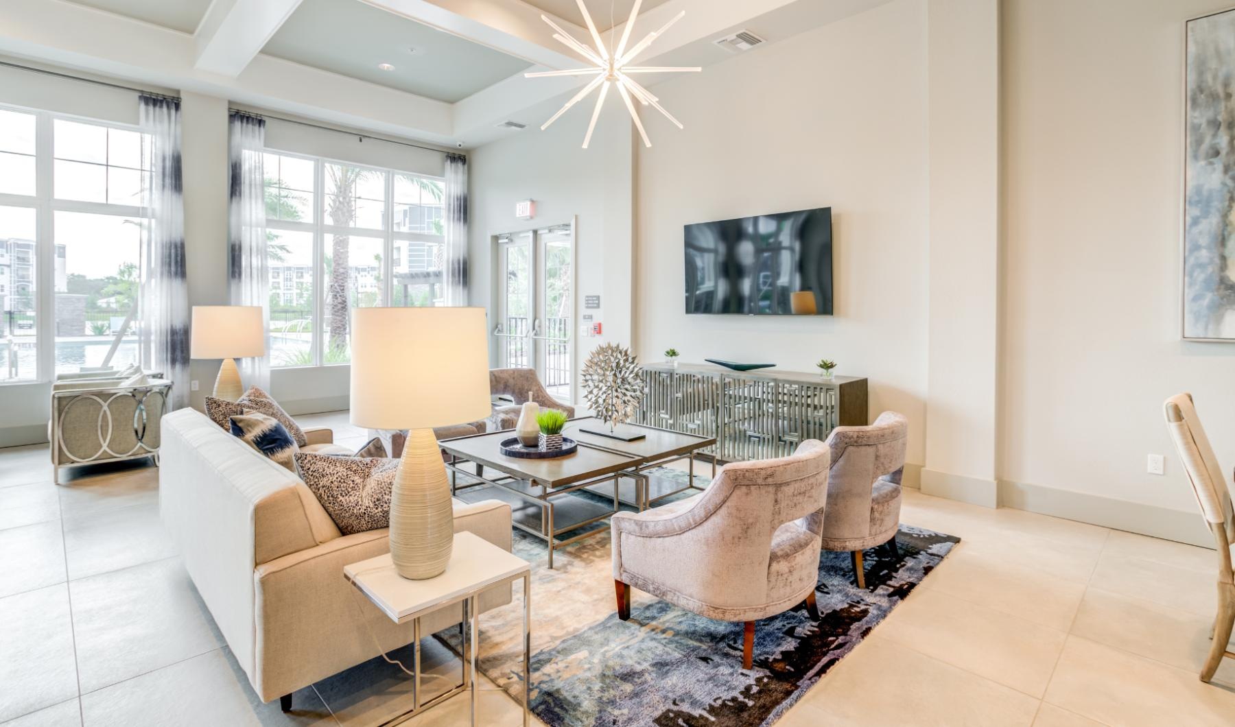 a lounge with a chandelier tv and seating