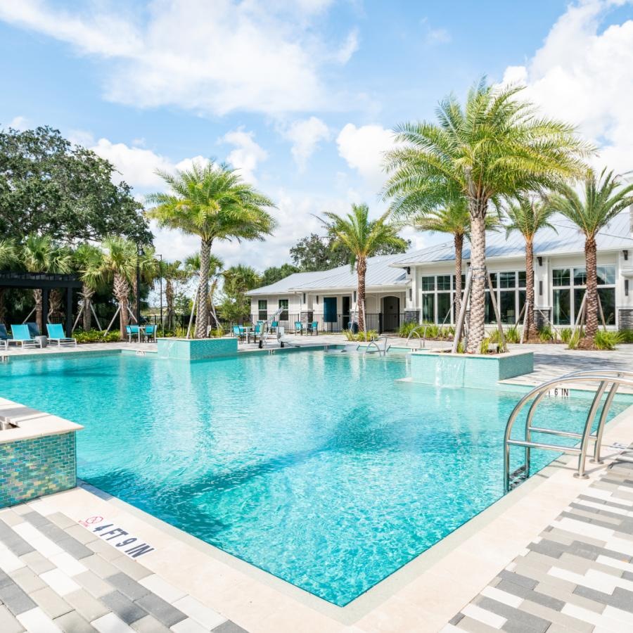 a swimming pool with palm trees and a building in the background