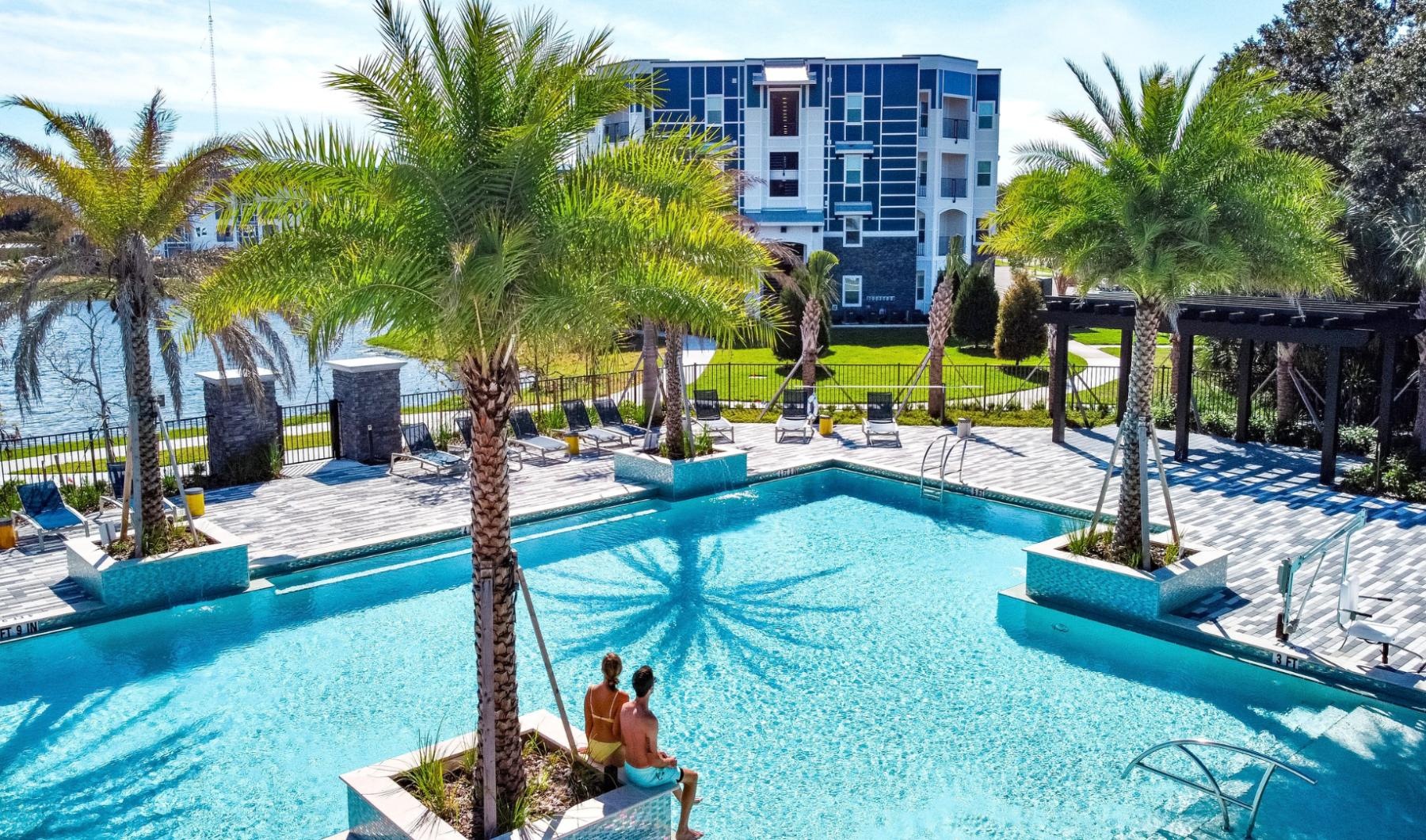 a group of people sitting by a pool by a building